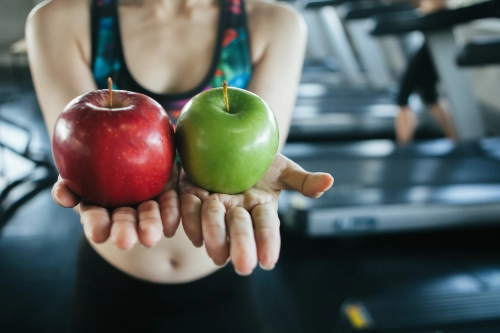 Mujer sosteniendo unas manzanas tras su entrenamiento en River Gym Club Collado Villalba, símbolo de nutrición práctica y hábitos saludables.