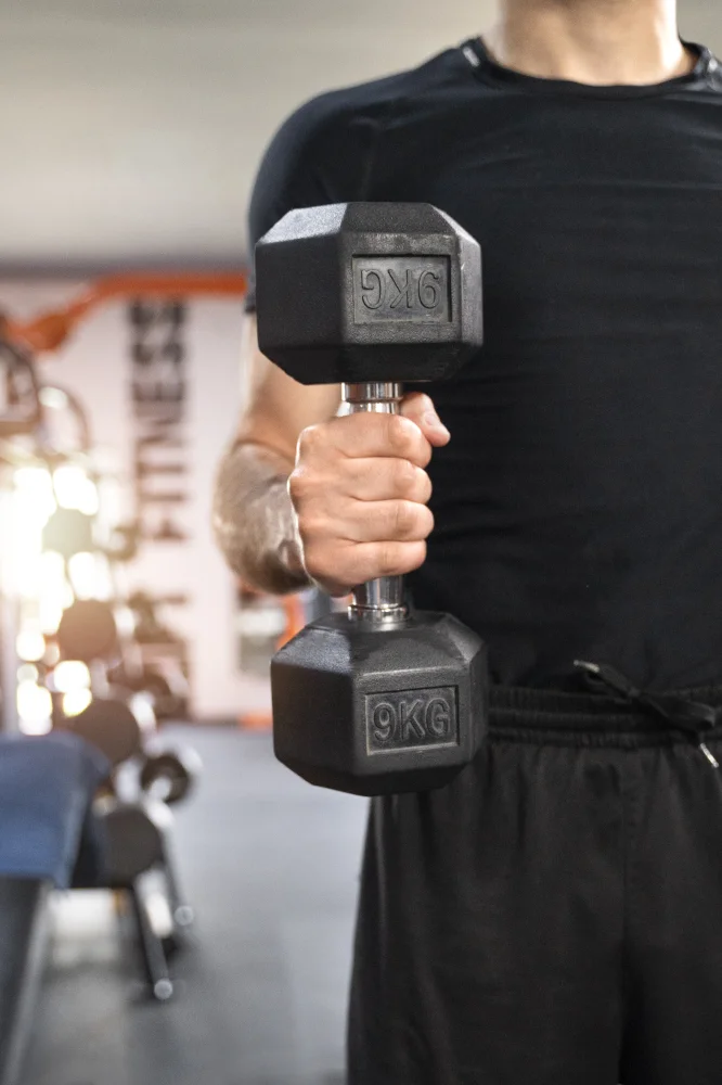 Hombre entrenando con mancuernas en River Gym Club Collado Villalba, ejemplo de entrenamiento completo y guiado para mejorar fuerza y bienestar.